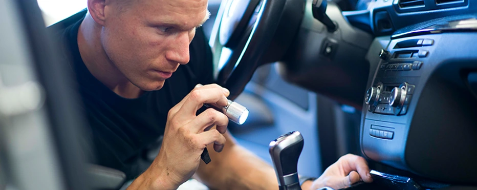 Mekaniker i bil som skinner lommelykt på radio